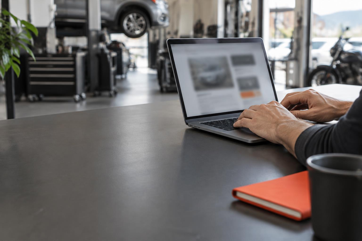 Arbeitsplatz für Webdesign mit Blick in eine Autowerkstatt